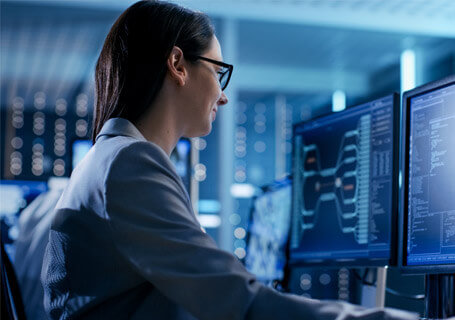 Una mujer trabajando en los sistemas informáticos con varios monitores